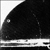 This original 1930 cloud-chamber photograph by Carl Anderson shows the track of a positively charged particle (thin track curving to the left) of electronic mass slowed down by passing upward through a lead plate (horizontal thick line).