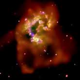 A Chandra X-ray image of The Antennae revealing loops of hot gas spreading out into intergalactic space, huge multimillion degree clouds, and bright emissions from neutron stars and black holes. The image is color coded: low, medium and high energy X-rays are red, green and blue.