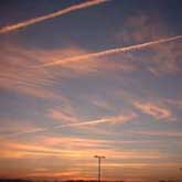 A large contrail being spread across the sky.